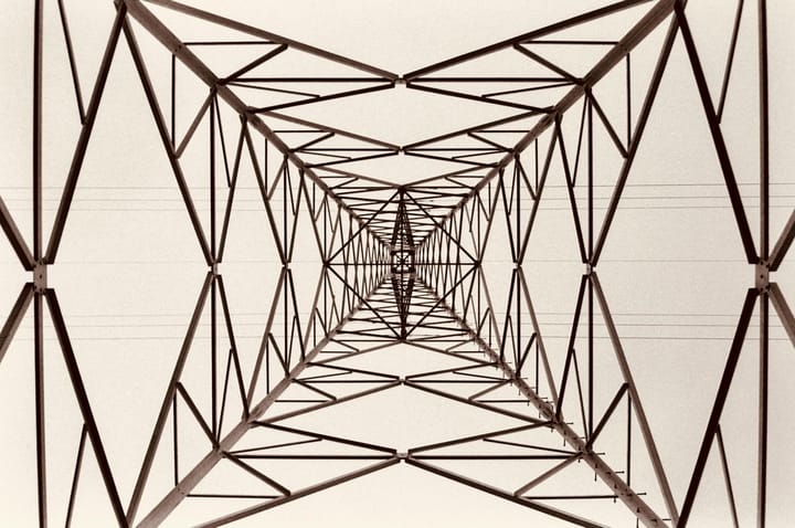 Looking up through the steel lattice of an electricity transmission tower, representing the interconnected roles and responsibilities in an enterprise AI governance structure.