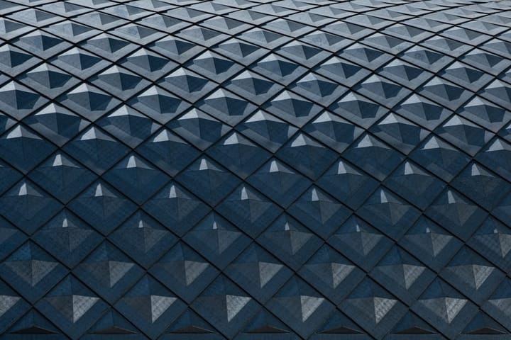 Abstract geometric pattern of teal and blue diamond shapes on a modern building facade
